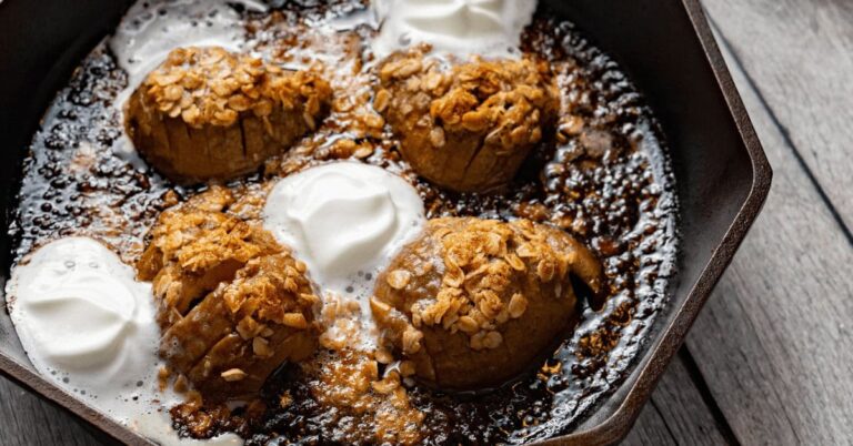 Baked Hasselback pears with oats, whipped cream, and caramel sauce in a skillet.