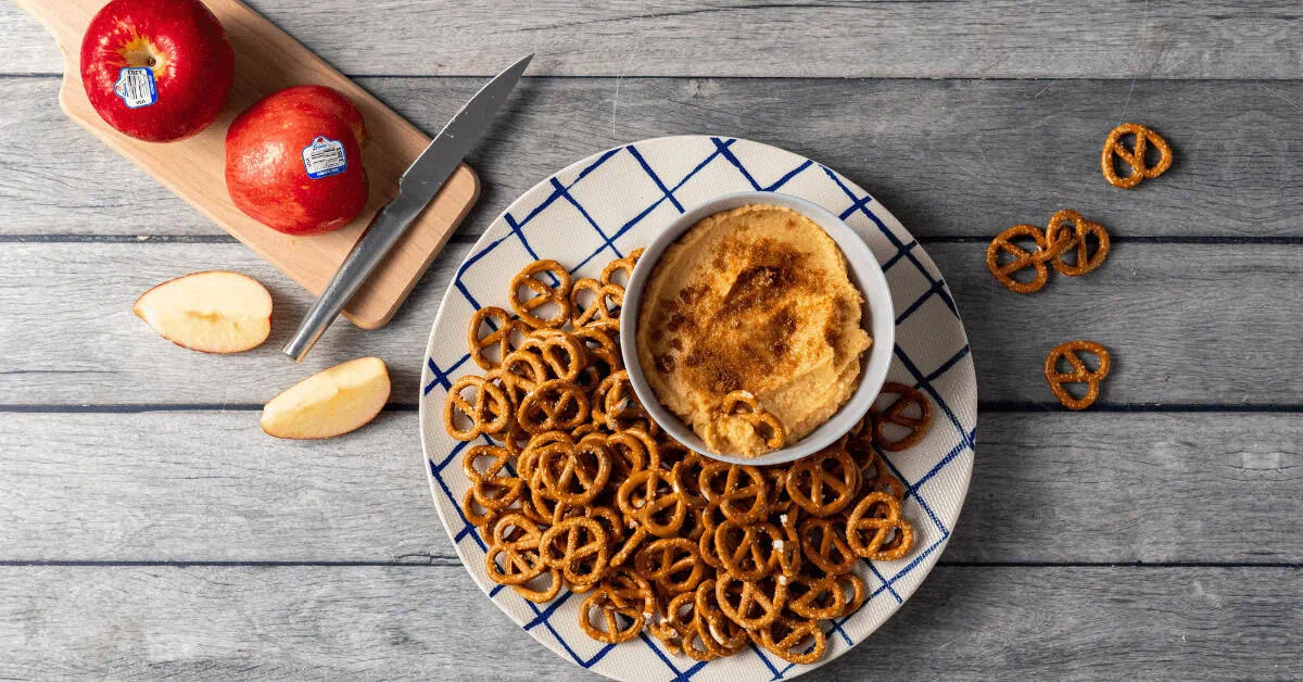 Apple butter hummus served with pretzels on a blue and white plate.