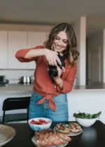 Woman taking photos of healthy fruit snacks in a modern kitchen.