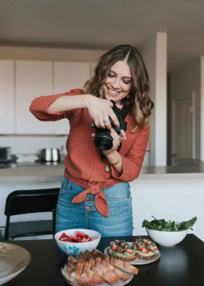 Woman taking photos of healthy fruit snacks in a modern kitchen.