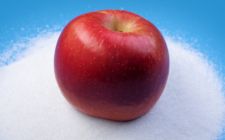 Fresh Fuji apple on snow with blue background, high-quality image for SEO.