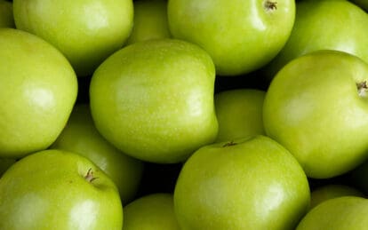 Fresh Granny Smith apples with bright green skin and smooth texture.