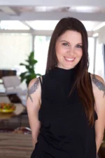 Smiling woman with tattoos in a modern kitchen setting.