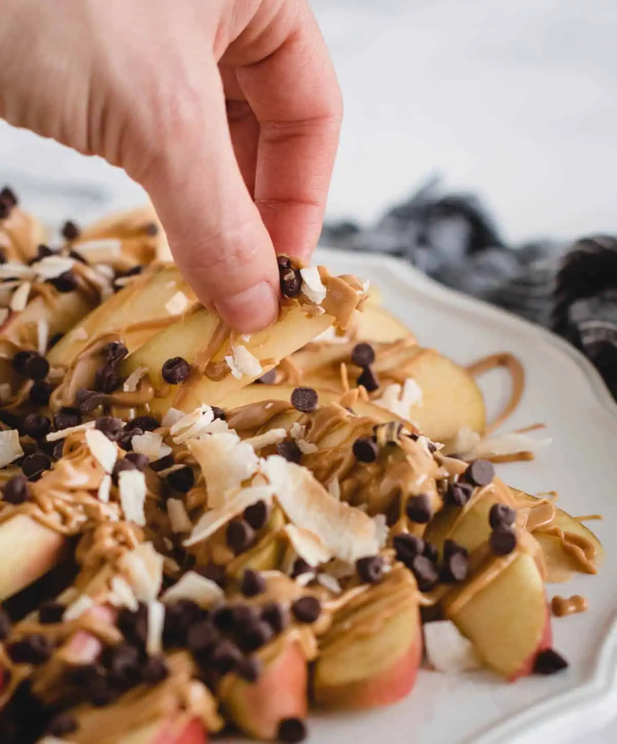 Apple nachos topped with peanut butter, coconut flakes, and chocolate chips.