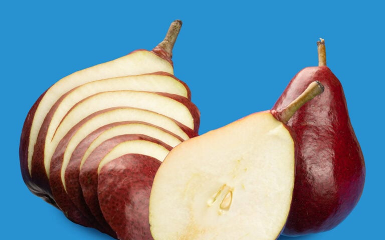 Fresh Starkrimson pears with sliced pieces on a blue background.
