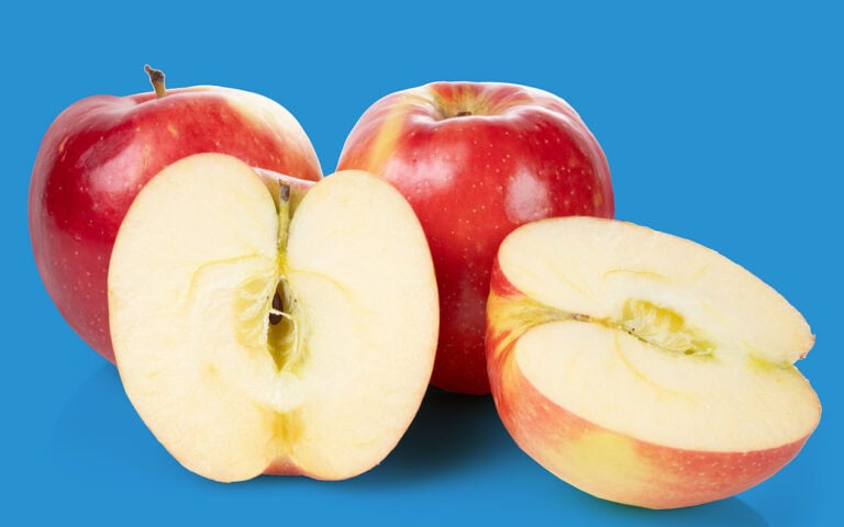 Fresh SweeTango apples with one cut in half showing juicy interior.