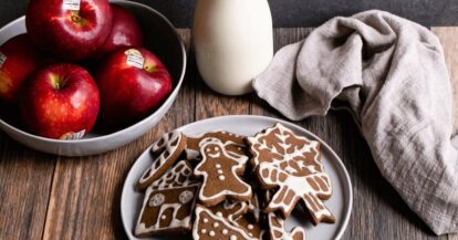 Gingerbread cookies with apple and milk on a wooden table for holiday treats.
