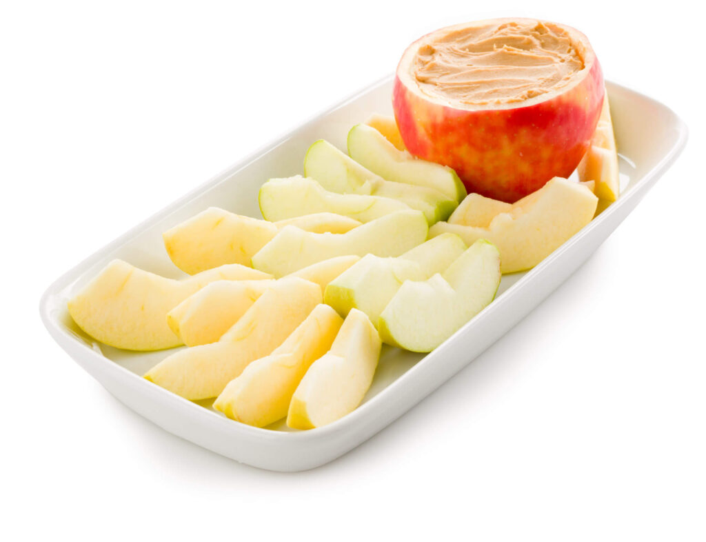 Sliced apples and a halved apple in a white dish for cooking or snacking.