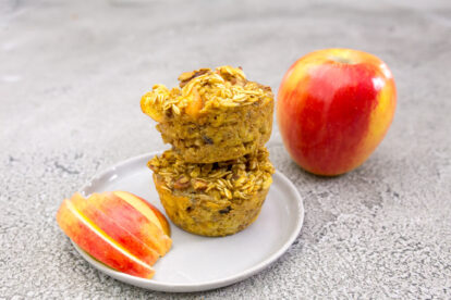 Apple oatmeal cups with fresh apple slices on a white plate.