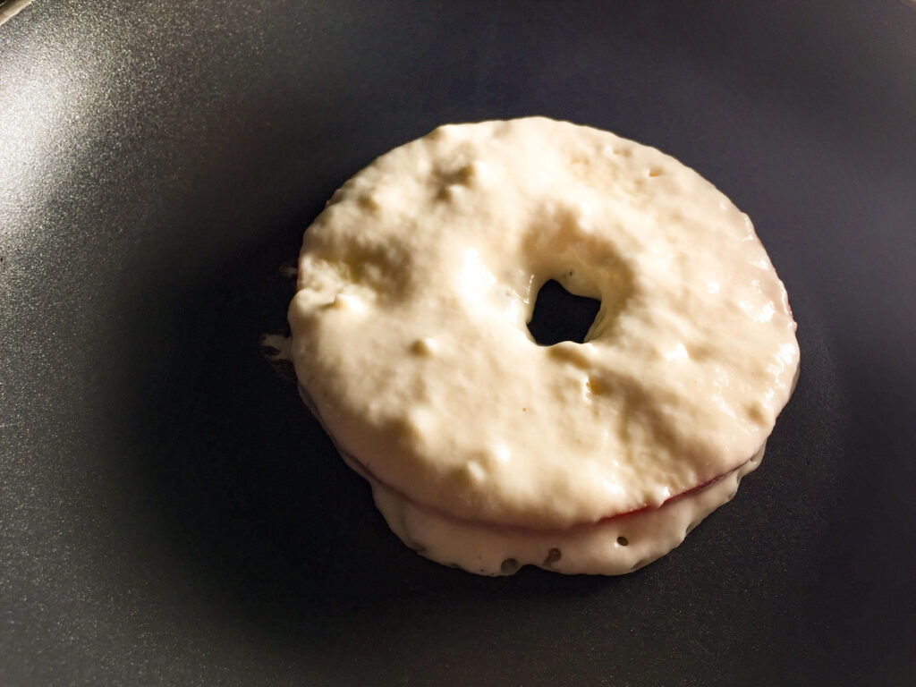 A glazed apple donut in a black frying pan, ready to be served.