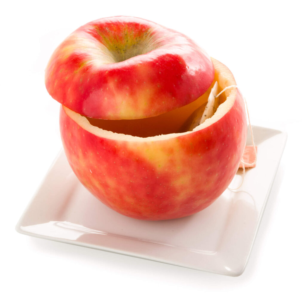 Red apple with a bite taken out, on a white plate, close-up view.