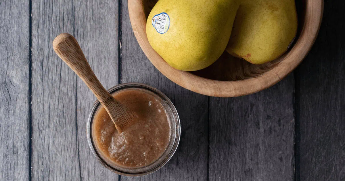Fresh pears with pear butter on a rustic wooden table.