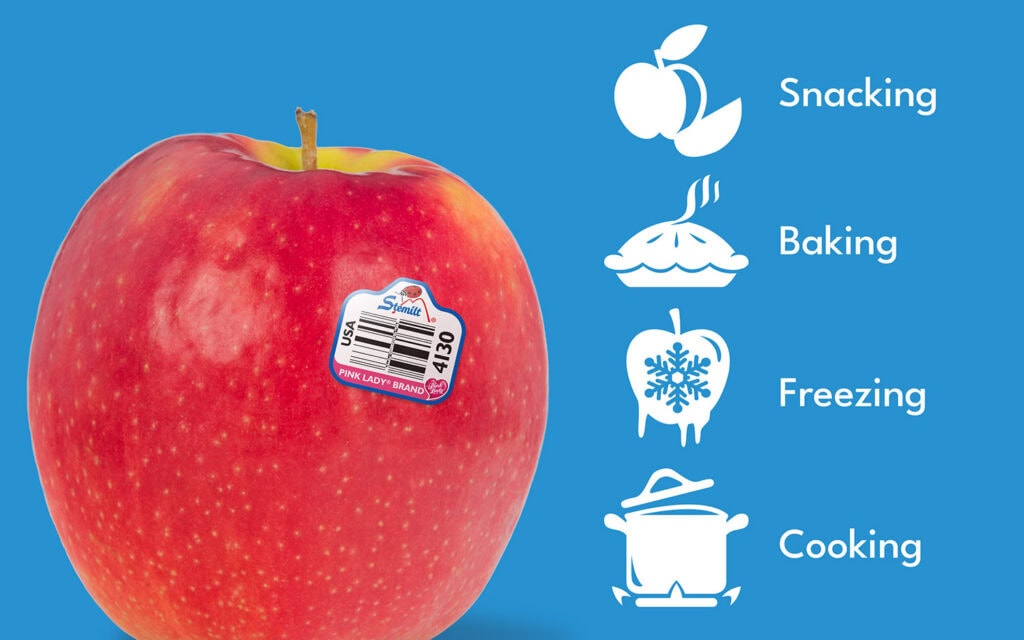 Fresh pink lady apple with a Stemilt sticker on a blue background.