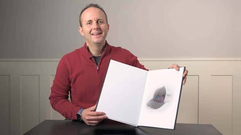 Man holding open book with colorful image inside, smiling at camera.