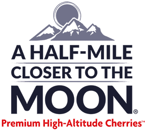 Close-up of ripe Moon Cherries with a mountain background and moon in the sky.