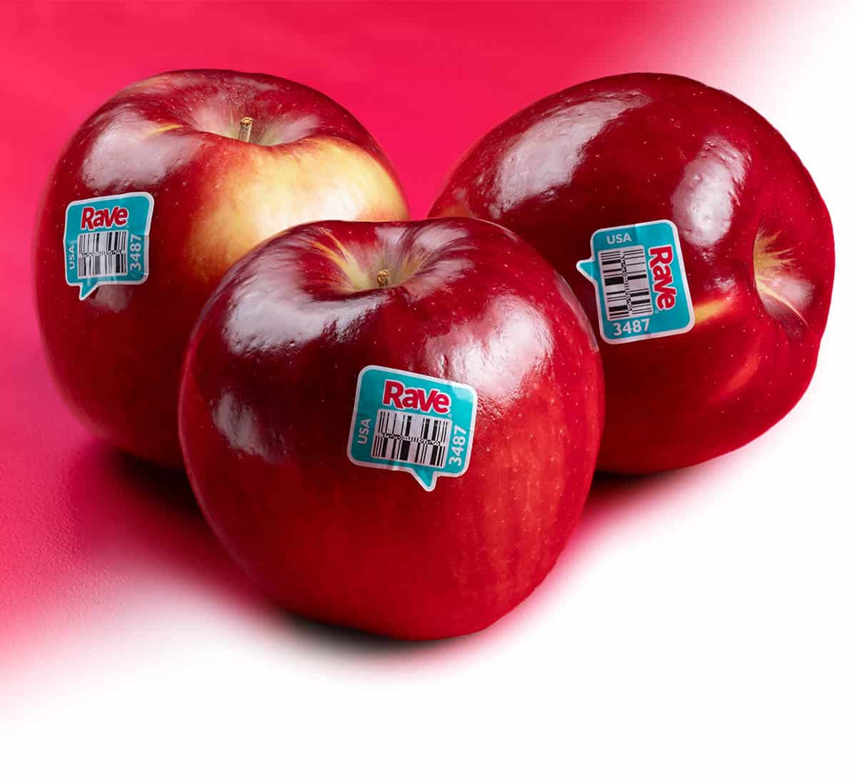 Fresh Rave&reg; apples with barcode stickers on a pink background.