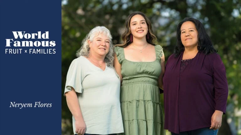 Family portrait of three women outdoors, smiling, with trees in background.