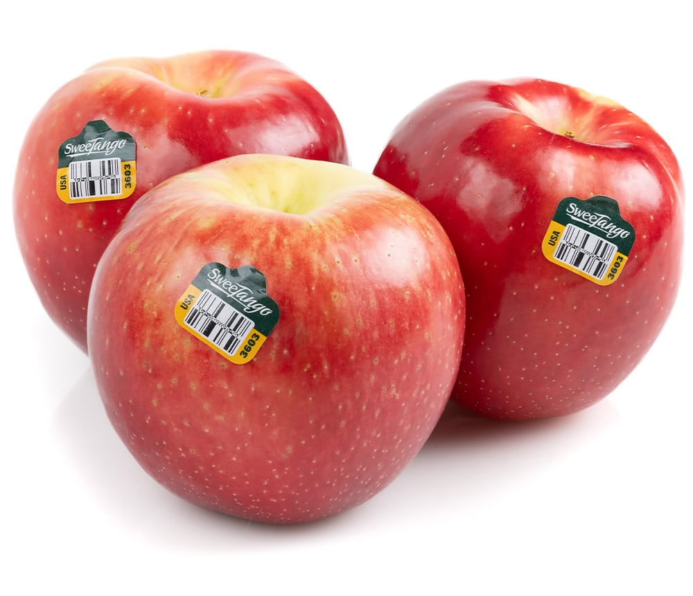 Fresh SweeTango apples with stickers on a white background.